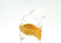 Slice the orange slice in a glass of water and make a spray on a white background. water spray in the air. a slice of citrus drops Royalty Free Stock Photo