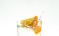 Slice the orange slice in a glass of water and make a spray on a white background. water spray in the air. a slice of citrus drops Royalty Free Stock Photo