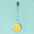 A slice of orange and three round drops of liquid gel on a blue background Medical concept Vitamin C Flat lay style