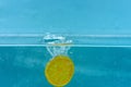 Slice of orange under water with transparent bubbles and water drops splashes. Fruit fall into water, blue background Royalty Free Stock Photo