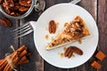 Slice of pecan caramel cheesecake, top view over wood