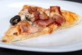 Slice of pizza with bacon cheese and olives lies on a plate Royalty Free Stock Photo