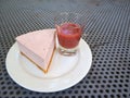 Slice of plain cheesecake with cranberry sauce on white plate decorated