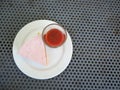 Slice of plain cheesecake with cranberry sauce on white plate decorated