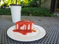 Slice of plain cheesecake with cranberry sauce on white plate decorated