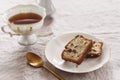 Slice of Pound Loaf Cake with raisins on white porcelain plate and cup of tea Royalty Free Stock Photo