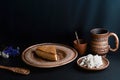 Slice of poured honey cake with cheese cream on a clay vintage plate, cup of milk, wooden spoon with cardamom, farm cottage cheese Royalty Free Stock Photo