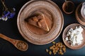 Slice of poured honey cake with cheese cream on a clay vintage plate, decorated with cocoa and almonds, wooden spoon with cardamom Royalty Free Stock Photo