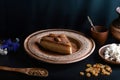 Slice of poured honey cake with cheese cream on a clay vintage plate, decorated with cocoa and almonds, wooden spoon with cardamom Royalty Free Stock Photo