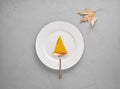 Slice of pumpkin pie over a spatula on a white plate over gray background with maple leaf Royalty Free Stock Photo