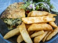 Slice of quiche on a serving plate placed beside some deep fried potato chips fries Royalty Free Stock Photo