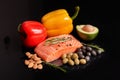 A slice of raw salmon fillet with a sprig of rosemary, red and yellow sweet peppers, almond nuts, green and black olives and slice