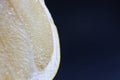 Slice of ripe fresh Pamela fruit with juice shot close-up on a black background.