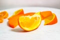 A slice of ripe orange in close-up  with blurred slices of persimmon and tangerine in the background Royalty Free Stock Photo