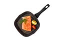 Slice of seasoned fresh salmon fish with dill and parsley on stone grill frying pan isolated on white background Royalty Free Stock Photo