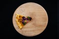 Slice of tasty pizza on a wooden board on a black background. View from above. Vegetarian pizza with cheese. One piece. Vegetable