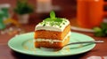 Slice of tasty sweet carrot sponge cake with cream decorated with mint leaf served on plate with spoon on table on colorful