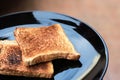 Slice toasted bread on black dish.