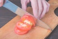 Slicing a tomato with a knife on a board
