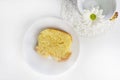 A slice of vanilla cake and daisy flower in a decorative cup