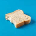 A slice of white bread with a bite taken out, placed on a solid blue background Royalty Free Stock Photo