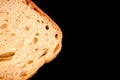 slice of white bread close up isolated on a black background. rough dappled textured surface chopped piece loaf of natural organic Royalty Free Stock Photo