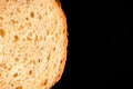 slice of white bread close up isolated on a black background. rough dappled textured surface chopped piece loaf of natural organic