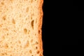 Slice of white bread close up isolated on a black background. rough dappled textured surface chopped piece loaf of natural organic Royalty Free Stock Photo