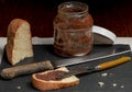 A slice of white bread, cut from a larger loaf, is spread with gianduia cream on a dark background