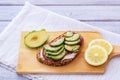 A slice of whole grain bread with seeds with cheese, salami  and sliced avocado for a healthy and tasty snack on a wood cutting Royalty Free Stock Photo