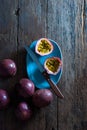 Slice and whole passion fruits with a kitchen knife in a pastel blue ceramic tray on a rustic wooden floor, top view. Royalty Free Stock Photo