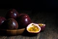 Slice and whole passion fruits in a wooden tray on a rustic wooden table. Royalty Free Stock Photo