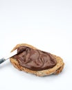Slice of whole wheat toast with healthy chocolate hazelnut spread, knife on white background, space for text Royalty Free Stock Photo