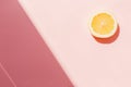 Slice of yellow lemon on trendy pink paper background flat lay, Royalty Free Stock Photo