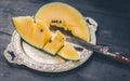 Slice yellow watermelon on a silver plate and knife on a dark wooden background Royalty Free Stock Photo