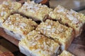 Sliced almond top on small square piece of cake on wooden tray serve at famous local bakery. Sweets gourmet. Crunchy texture.