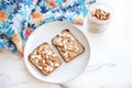 sliced almonds sprinkled over almond butter toast on a patterned napkin