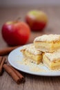 Sliced apple pie made from shortcrust pastry with cottage cheese cream and apple wedges on a white plate on a wooden background Royalty Free Stock Photo