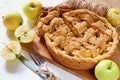 Sliced apple pie on the wooden board decorated with fresh green apples, sugar cubes, spices, vintage knife and fork