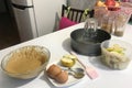 Sliced apples in a baking dish. Nearby is dough and other ingredients and tools for making charlotte. Autumn pie with apples