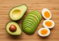 Sliced avocado and hard-boiled eggs on a wooden surface. The avocado is displayed in Royalty Free Stock Photo