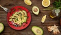 Sliced avocado on a red plate on a a rustical wooden table
