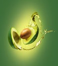 Sliced avocado with splashes isolated on a green background Royalty Free Stock Photo
