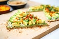 sliced avocado topping on a raw vegan pizza, with chili flakes