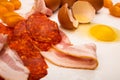 Sliced bacon and sausage, tomatoes and a broken chicken egg on a white background. Close up Royalty Free Stock Photo