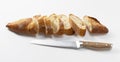 A sliced baguette and a bread knife on a white background Royalty Free Stock Photo