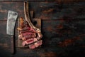 Sliced barbecued tomahawk rib tip with rosemary, salt and herbs medium rare, on wooden serving board, on old dark  wooden table Royalty Free Stock Photo