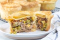 Sliced beef pot pie on plate, pies on cooling rack, horizontal, closeup Royalty Free Stock Photo