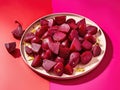 Sliced beets on a plate on a pink background