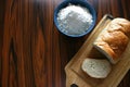 Sliced bread on the cutting board with blue bowl with wheat flour on the wooden table. Royalty Free Stock Photo